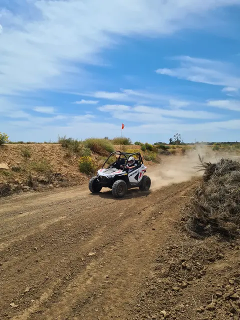 Kids buggy taking a curve on the dirt circuit, leaving a trail of dust