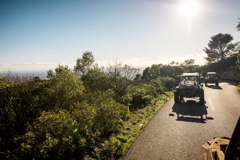 Buggies driving on a narrow paved road with a wide view over the landscape