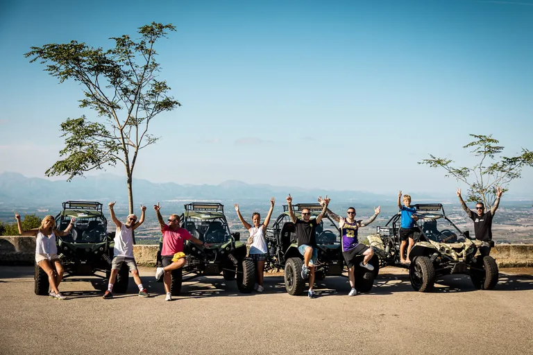 Group cheering in front of their road buggies at a viewpoint