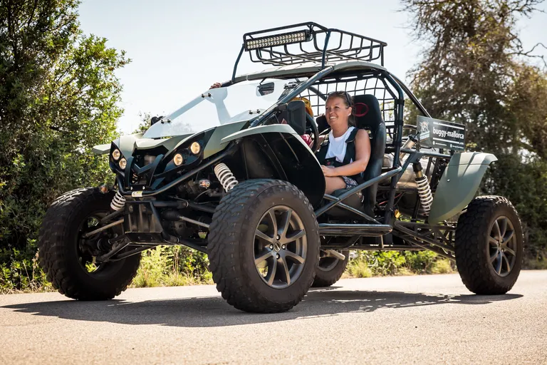 Green two-seater road buggy with two smiling people on a paved road