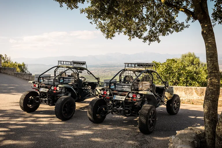 Two parked road buggies at a viewpoint overlooking the plain and mountains